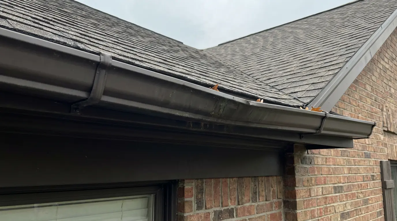 a black aluminum gutter system that is sagging a little bit in the middle